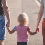 Child holding hands with two adults